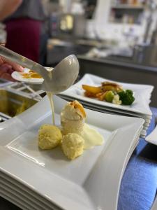 a white plate with a spoon with food on it at Seehotel Hoffmann in Steindorf am Ossiacher See