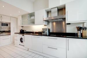 a kitchen with white cabinets and a washer and dryer at Excel London City Airport Seagull Lane Royal Victoria 2 Bedrooms Apartments in London