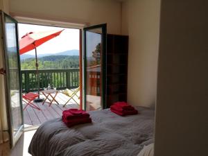 a bedroom with a bed and a balcony with an umbrella at LES JARDINS CELESTES in Saint-Genest-de-Bauzon