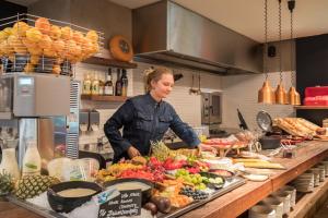 een vrouw die in een keuken staat om eten te bereiden bij Van Heeckeren Hotel in Nes