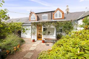 a house with a garden and a yellow door at The Nest- Cosy Holiday Cottage in Errol