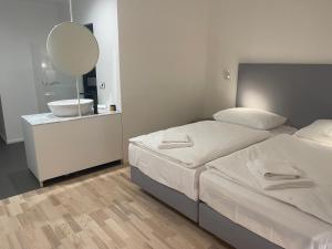 een slaapkamer met 2 bedden, een wastafel en een spiegel bij Hotel Praha Liberec in Liberec