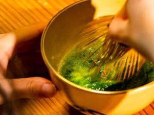 a person is stirring a bowl with a whisk at Udatsuya in Osaka