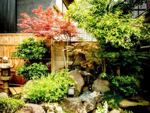 a garden with rocks and trees and a fence at Udatsuya in Osaka