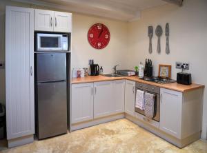 a kitchen with a refrigerator and a clock on the wall at Cabriere Cottage in Franschhoek