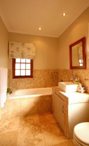 a bathroom with a tub and a sink and a toilet at Cabriere Cottage in Franschhoek