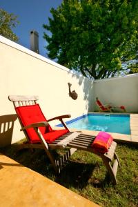 a red chair sitting next to a swimming pool at Cabriere Cottage in Franschhoek