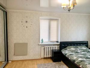1 dormitorio con 1 cama y reloj en la pared en Аппартаменты в самом центре Площадь-Вал en Chernihiv
