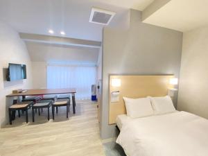 広島市にあるたかのばしホテルのベッド、テーブル、椅子が備わるホテルルームです。