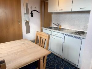 una pequeña cocina con mesa de madera y fregadero en Appartement Möhlkiek en Nordstrand