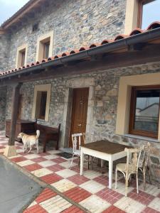 a dog standing in front of a house with a table and chairs at VILLA BERENGUELA in Boca de Huérgano