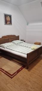 Cette chambre comprend un grand lit avec un cadre en bois. dans l'établissement Smještaj Slavonija, à Daruvar