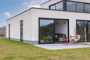 a white house with glass doors and red chairs at Whaaw Westende-bad in Middelkerke
