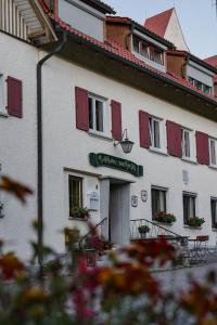 ein weißes Gebäude mit roten Rollläden darauf in der Unterkunft Gasthaus Hirsch in Wangen im Allgäu