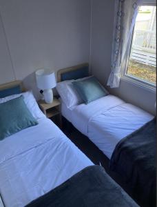 two beds in a small room with a window at KellysHolidayHomes 26 Willerby 2 bedrooms caravan in Weeley