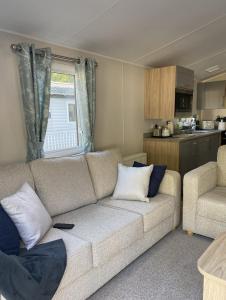 ein Wohnzimmer mit einem Sofa und einer Küche in der Unterkunft KellysHolidayHomes 26 Willerby 2 bedrooms caravan in Weeley