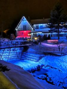 a house lit up in the snow at night at Noclegi Hexe in Żegocina