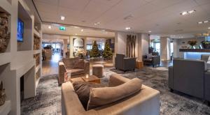 a lobby with couches and chairs in a building at Fletcher Zuiderduin Beachhotel in Westkapelle