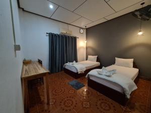 a room with two beds and a table in it at Saphaothong guesthouse in Vang Vieng