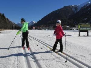 two women are cross country skiing in the snow at Gästehaus Hoamat'l in Bach