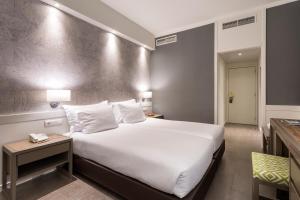 a hotel room with a large white bed and a table at AP Eva Senses in Faro