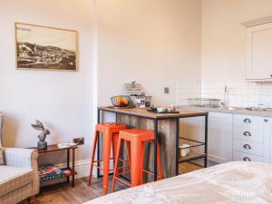 una cocina con mesa y 2 taburetes naranjas en Lewis Hunton Suite en Saltburn-by-the-Sea