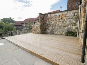 un patio con una pared de ladrillo y una terraza de madera en Lewis Hunton Suite en Saltburn-by-the-Sea