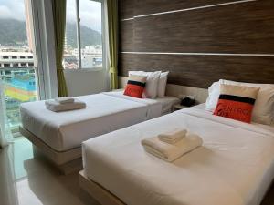 two beds in a hotel room with a window at Centro One Bangla in Patong Beach