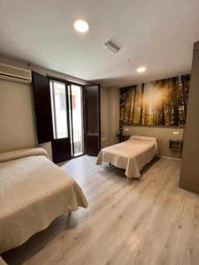 a bedroom with two beds and a painting on the wall at Hostal Viena Plaza Nueva in Granada
