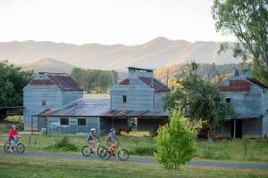 three people riding bikes down a road in front of buildings at Jamieson Cottage in Myrtleford