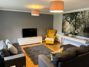 a living room with two couches and a flat screen tv at Flat Three, 212 Eaglesham Road, East Kilbride, Glasgow in East Kilbride