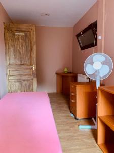 1 dormitorio con 1 cama rosa y ventilador en Williams Village Bowling & Country Club, en Budapest