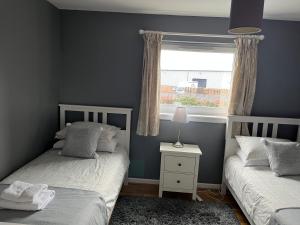 1 dormitorio con 2 camas individuales y ventana en Flat Three, 212 Eaglesham Road, East Kilbride, Glasgow en East Kilbride