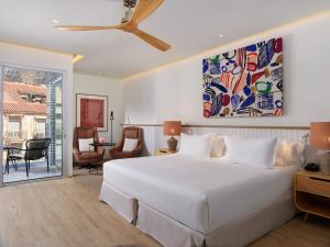 a bedroom with a large white bed and a living room at H10 Croma Málaga in Málaga