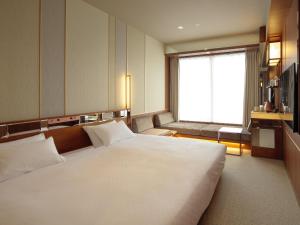 duże białe łóżko w pokoju z oknem w obiekcie Candeo Hotels Nagasaki Shinchi Chinatown w mieście Nagasaki