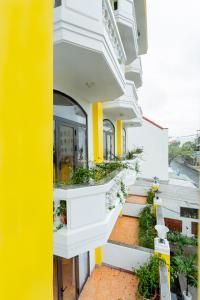 ホイアンにあるSea and Sand Hotelの白と黄色の壁と植物のある建物
