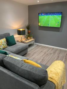 a living room with a couch and a tv on the wall at Me Old Abode Entire Garden Cabin near the Sea in Kent