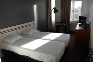 een slaapkamer met een groot wit bed in een kamer bij Fletcher Stadshotel Den Haag in Den Haag