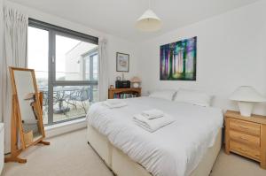 sypialnia z białym łóżkiem i dużym oknem w obiekcie Superb apartment with terrace near the river in Putney by UnderTheDoormat w Londynie