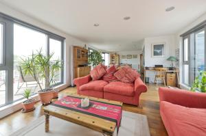 a living room with red furniture and large windows at Superb apartment with terrace near the river in Putney by UnderTheDoormat in London