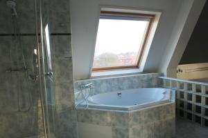 a bathroom with a bath tub and a window at Fletcher Stadshotel Den Haag in The Hague