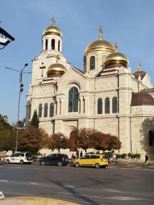 uma igreja com cúpulas douradas e carros estacionados em frente dela em Aпартамент 5 em Varna City