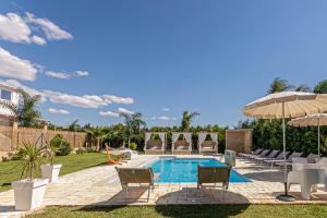 een achtertuin met een zwembad met stoelen en een parasol bij Resort Almaredamarra con piscina e idromassaggio sul mare in Torre San Giovanni Ugento