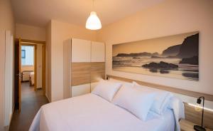 una camera da letto con un letto bianco e un dipinto sul muro di Area Suites a Jove