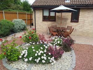 a garden with a table with an umbrella and flowers at Rose Bungalow In Carlton Colville in Pakefield