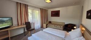 een hotelkamer met een bed en een televisie bij Hotel Sommerer in Saalbach Hinterglemm