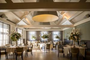 una sala de banquetes con mesas y sillas y una gran lámpara de araña en Fletcher Hotel-Restaurant Teugel Uden-Veghel, en Uden