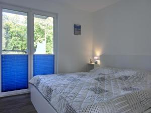 ein weißes Schlafzimmer mit einem Bett und zwei Fenstern in der Unterkunft Ferienwohnung KWi 12 EG in Graal-Müritz
