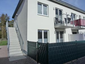 ein weißes Haus mit einem Zaun und einer Treppe in der Unterkunft Ferienwohnung KWi 12 EG in Graal-Müritz