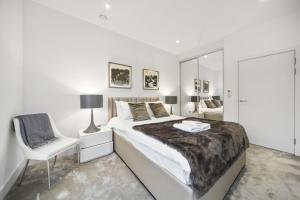 a white bedroom with a large bed and a chair at Lux Apartments next to Oxford Circus FREE WIFI & AIRCON by City Stay Aparts London in London
